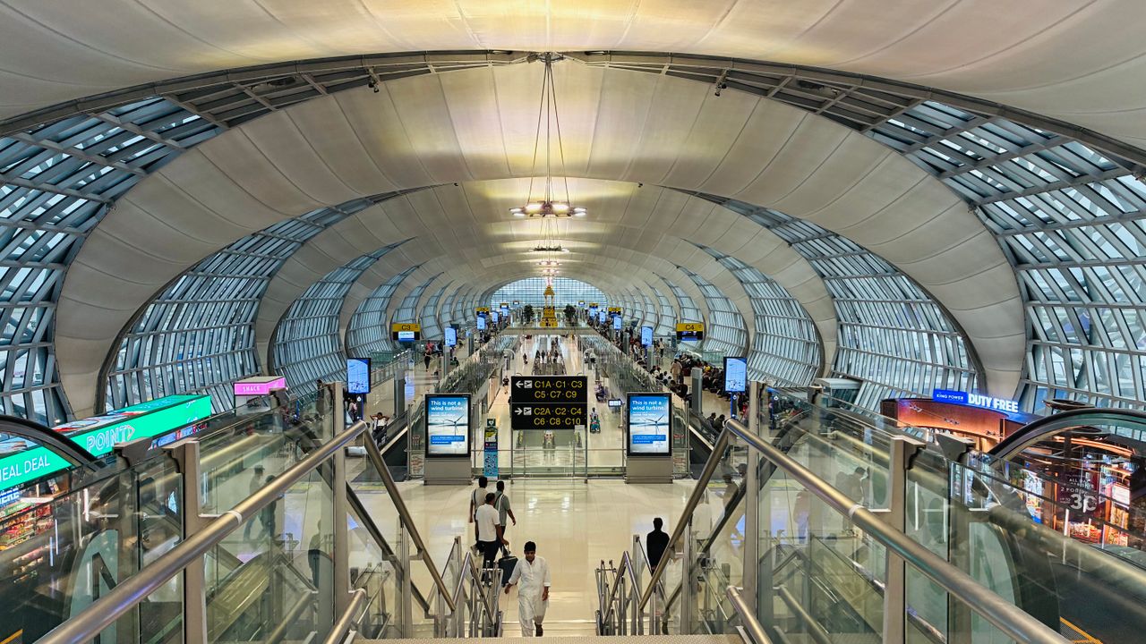 Bright airport terminal concourse with travellers heading toward the departure gates